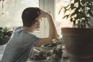 A man looks out the window wondering if he is exhibiting some of the signs of depression in men