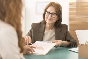 A woman explains mental health insurance coverage options to a woman with mental health insurance Houston provides