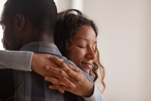 a husband and wife hug after he learns how to help someone with anxiety