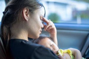A woman holds her baby thinking about her need for Houston postpartum depression therapy from a postpartum depression psychiatrist