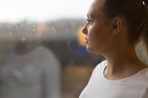 A woman looks out the window thinking about her need for seasonal depression treatment